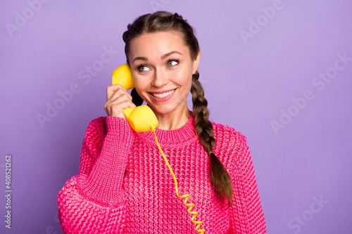 Portrait of young lovely pretty cheerful smiling girl look copyspace speaking on phone isolated on violet color background photo