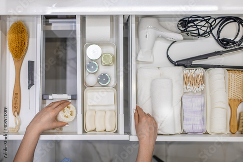 Canvastavla Top view of woman hands neatly organizing bathroom amenities and toiletries in drawer in bathroom