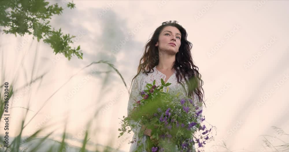 girl with interested look in field with flowers in her hands enjoys nature girl with interested look in field with flowers in her hands enjoys nature