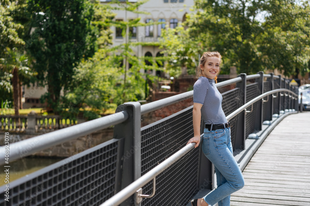young woman laughing woman looking at camera and leaning on a bridge railing