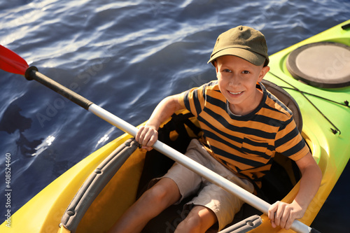 Happy little boy kayaking on river, above view. Summer camp activity