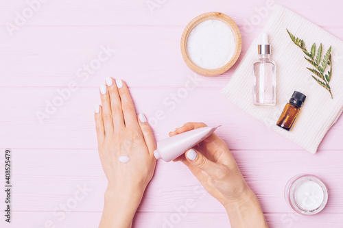 Top view of female hands applying moisturizing lotion