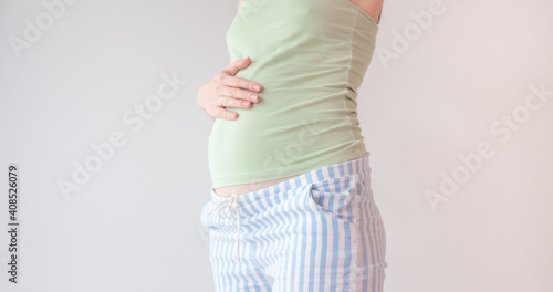 Pregnant woman holding hands on her belly. Belly of a pregnant woman on 16 week, 4 month. A woman is stroking her belly in the second trimet of pregnancy