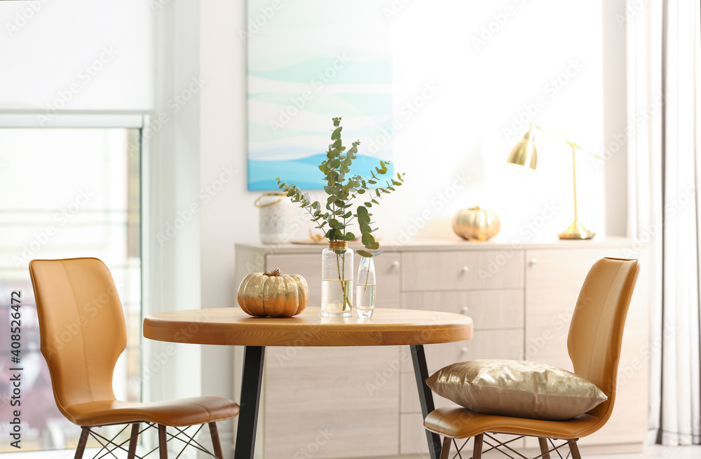 Fototapeta premium Beautiful living room interior with eucalyptus branches and decorative pumpkin on table