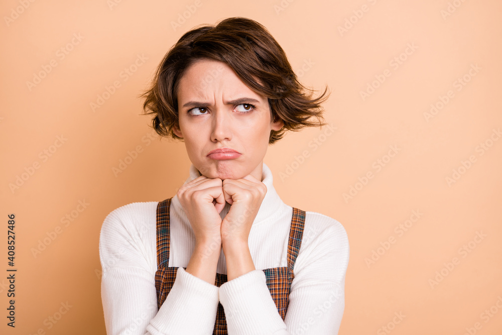 Photo portrait of gloomy grumpy schoolgirl looking at blank space sad isolated on pastel beige color background Photo portrait of gloomy grumpy schoolgirl looking at blank space sad isolated on pastel beige color background