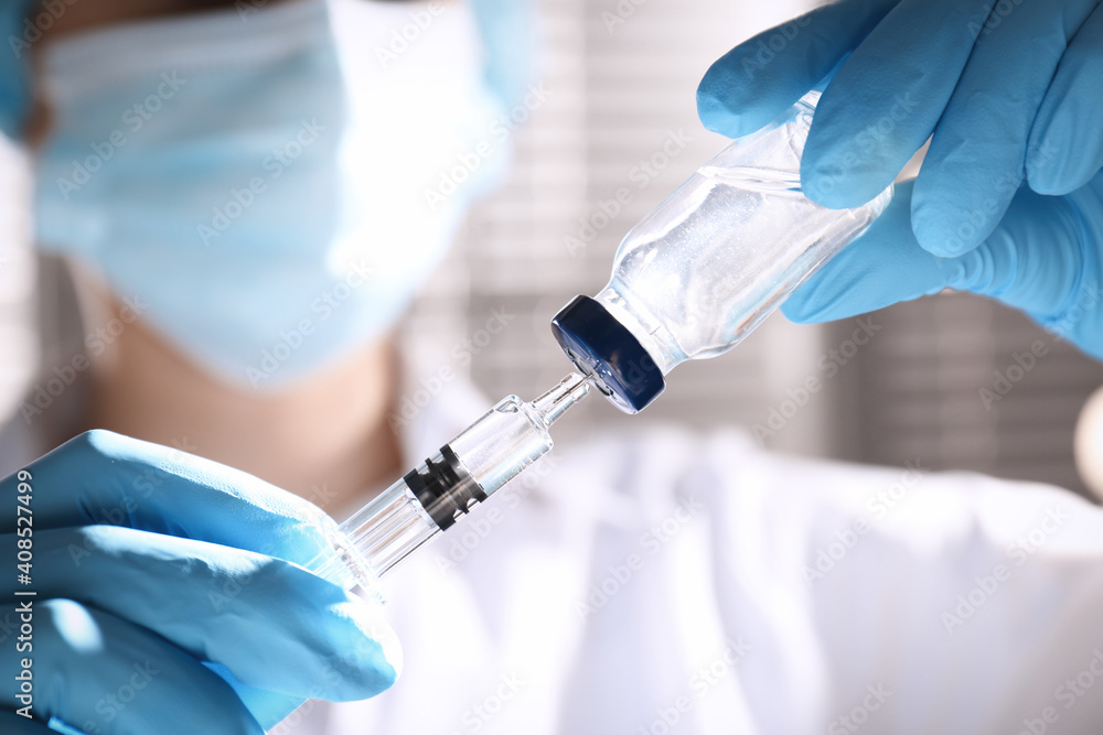 Woman filling syringe with vaccine from vial on blurred background, closeup Woman filling syringe with vaccine from vial on blurred background, closeup