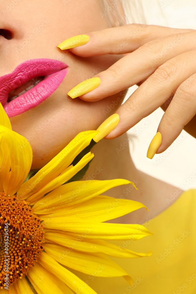 Fashionable manicure on long nails covered with yellow nail polish on a woman with a sunflower. Fashionable manicure on long nails covered with yellow nail polish on a woman with a sunflower.