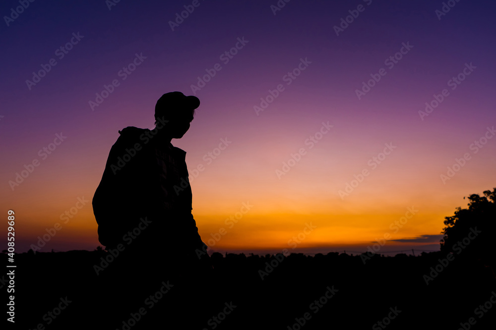 silhouette dark young man wearing a hat standing emotions with evening Twilight sky with cloud in the winter season at sunset Abstract background.Copy space for your
