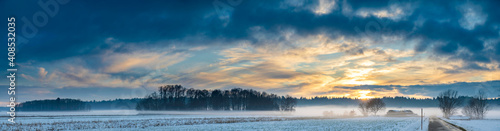 Landscape panorama with road, white fields cover by snow and sunset sky. © Przemyslaw Iciak