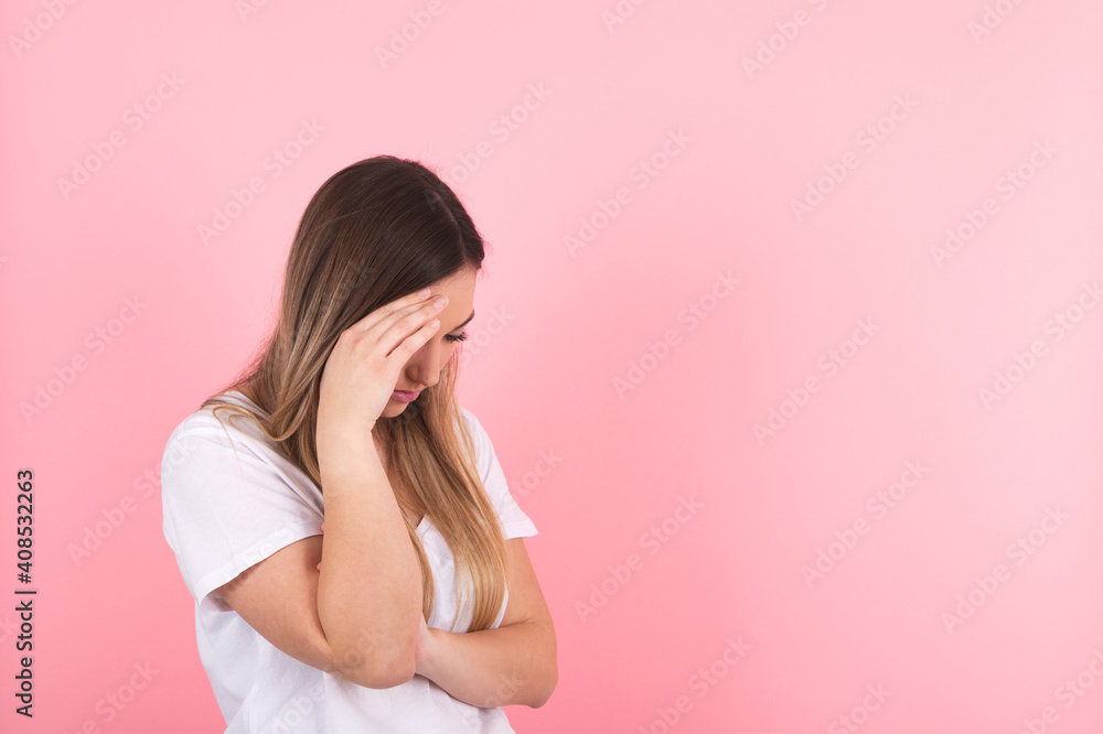 young woman shows sadness by hiding behind her hand young woman shows sadness by hiding behind her hand