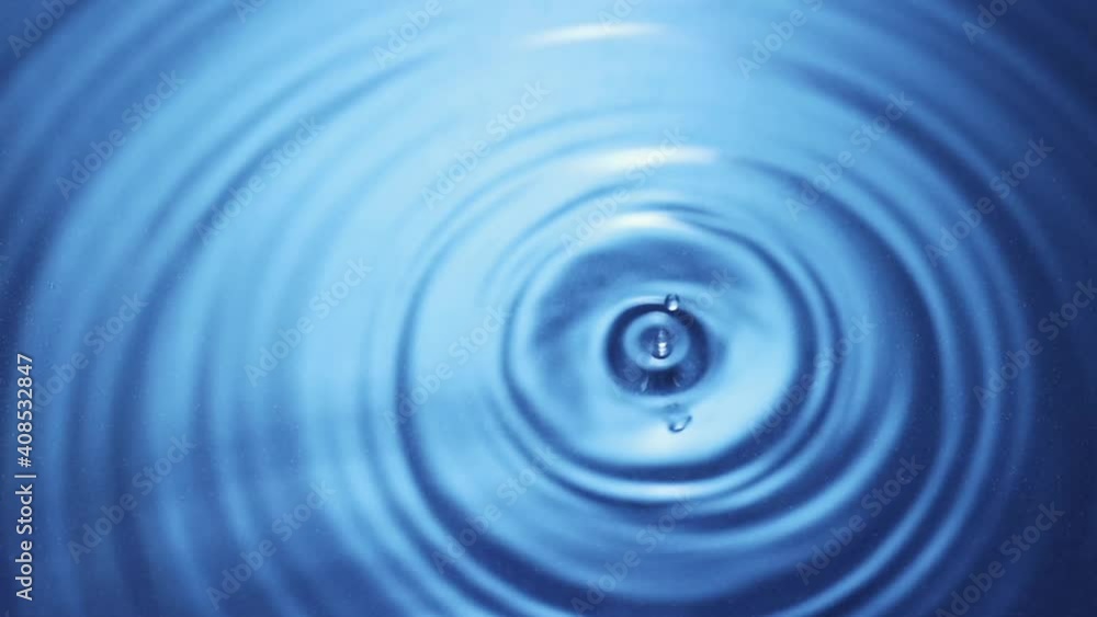 Top view of drop falls into water and diverging circles of water on blue background in slow motion Top view of drop falls into water and diverging circles of water on blue background in slow motion