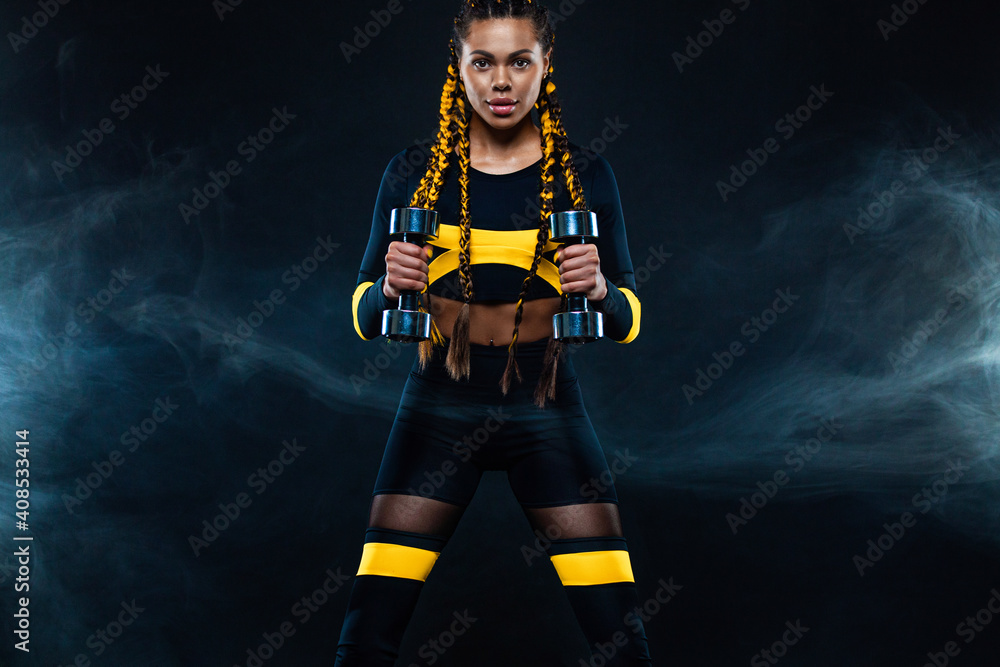 Obraz premium African american woman athlete bodybuilder. Muscular young fitness sports woman workout with dumbbells in fitness gym.