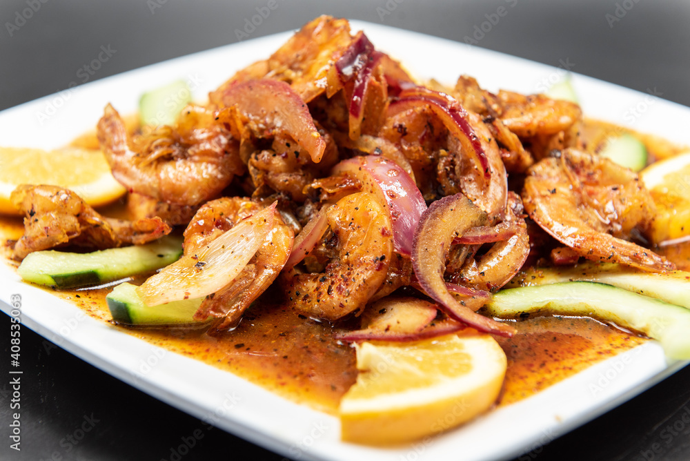 Spicy plate of Mexican flavored shrimp garnish with orange slices and cucumber
