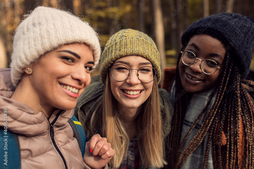 Three female friends enjoying hiking in forest and making selfie with smartphone. Three female friends enjoying hiking in forest and making selfie with smartphone.