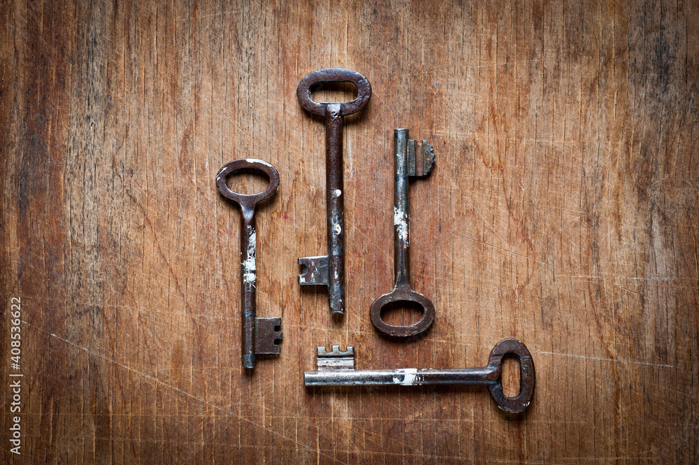 Old iron door keys lying on an old wooden surface. Old iron door keys lying on an old wooden surface.