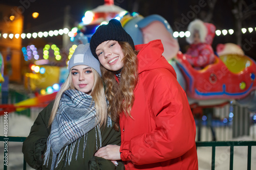 Portrait of two teenage girls on the background of an evening amusement park