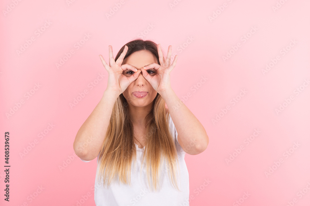 young woman having fun making glasses shape with hands. People emotions concept