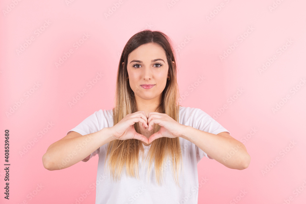 Young beautiful woman smiling doing heart symbol shape with hands. Romantic concept Young beautiful woman smiling doing heart symbol shape with hands. Romantic concept