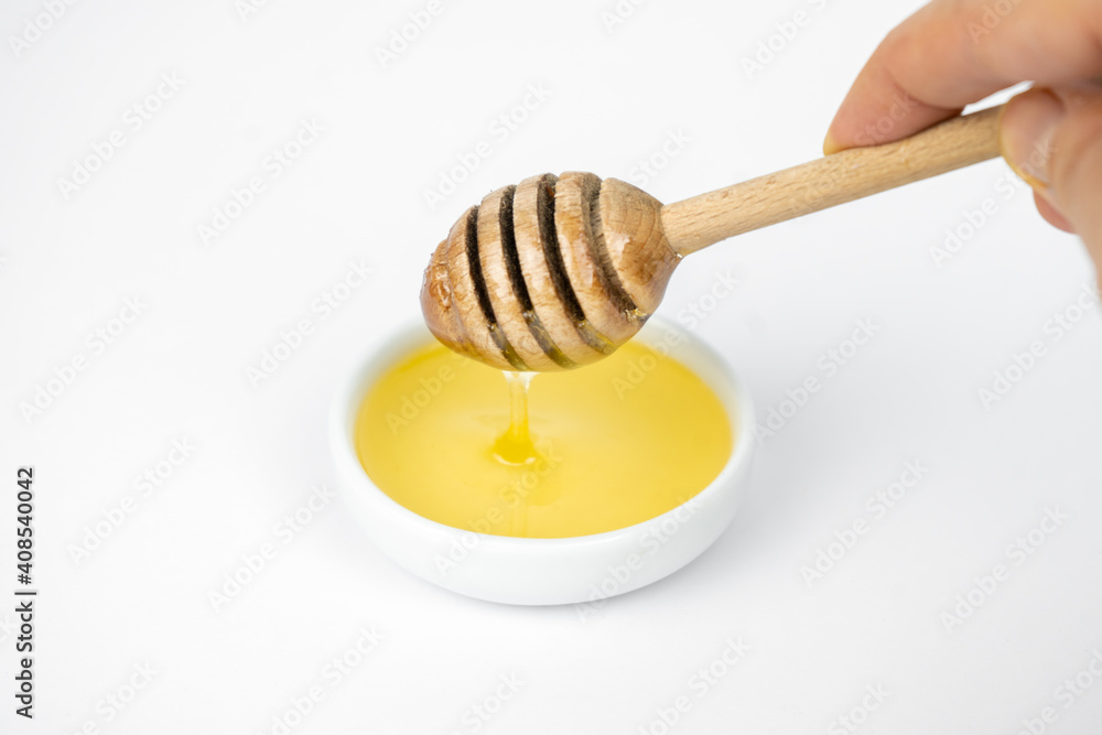 Liquid honey pouring with wooden stick in small white plate. Liquid honey pouring with wooden stick in small white plate.