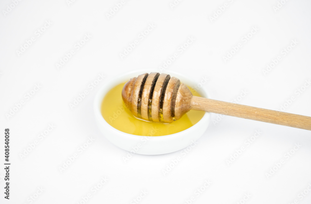 Liquid honey pouring with wooden stick in small white plate. Liquid honey pouring with wooden stick in small white plate.