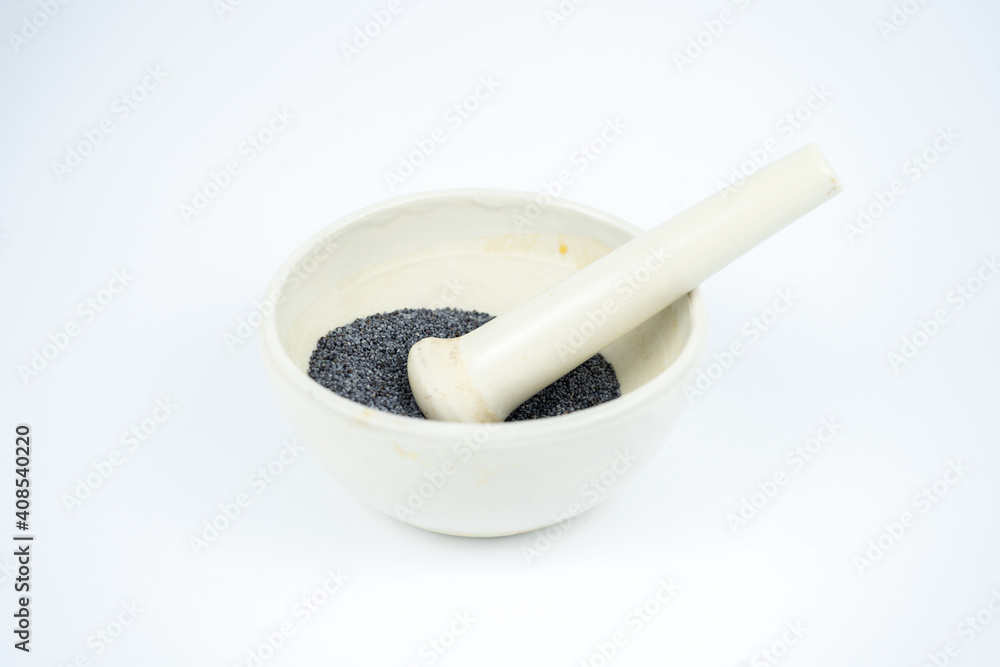 Poppy seeds in a special white bowl with the pounder. Isolated on white background Poppy seeds in a special white bowl with the pounder. Isolated on white background
