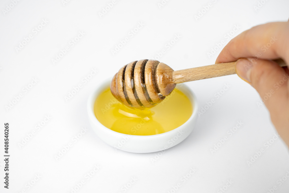 Liquid honey pouring with wooden stick in small white plate. Liquid honey pouring with wooden stick in small white plate.