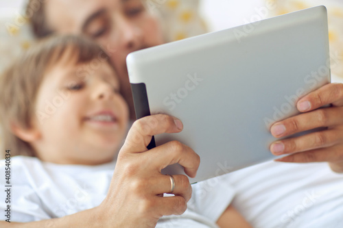 Son and father are playing a computer game on a tablet. . High quality photo