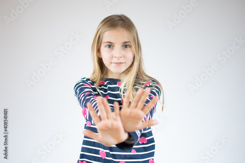 Little girl over white background doing stop sing with palm of the hand. Warning expression with negative and serious gesture on the face.