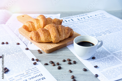 Close Up of Fresh Baked Croissant on wood table with Coffee Mug and news paper on Relaxing Morning at Home, Bread and coffee, breakfast Healthy food of the city life