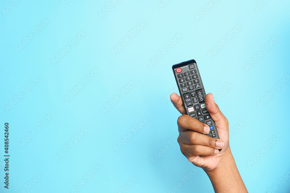 close up of man hand holding tv remote on blue background close up of man hand holding tv remote on blue background