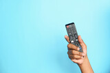 close up of man hand holding tv remote on blue background 