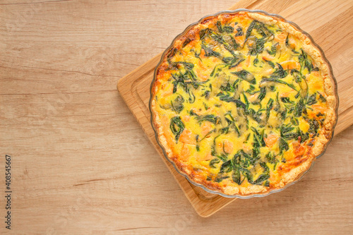Seafood salmon fish and spinach leaves quiche pie - homemade recipe pie on wooden table background with copy space, selective focus. Top view