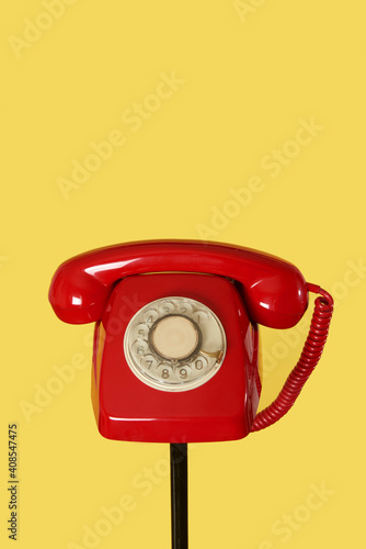 red rotary dial telephone on a black stand