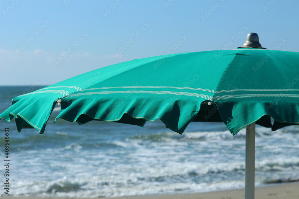 detail of green beach umbrella. blue sea and sky as background.