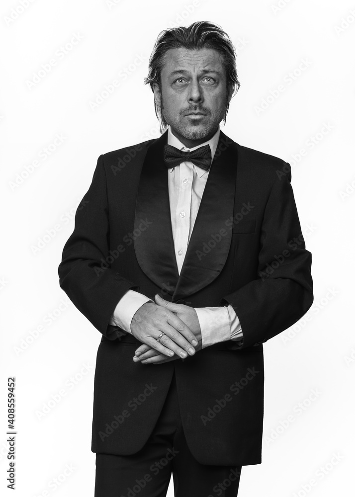 Man in tuxedo in front of white background. Black and white photo. Man in tuxedo in front of white background. Black and white photo.