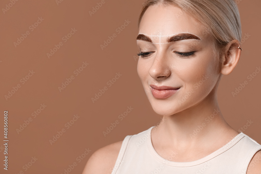 Young woman with marking for eyebrow correction on color background Young woman with marking for eyebrow correction on color background