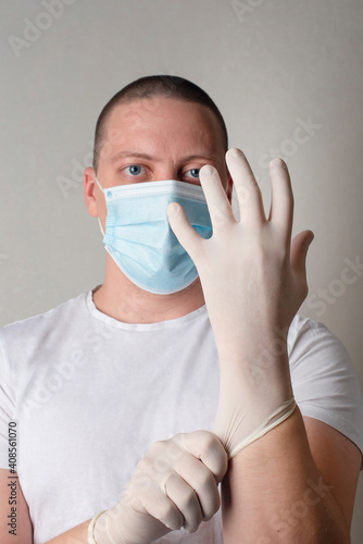 The doctor or nurse or scientist putting on white disposable gloves.