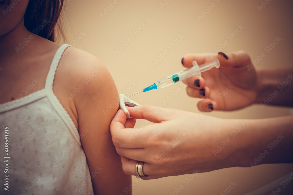 Little girl in the doctor's office is vaccinated. Syringe with vaccine against covid-19 coronavirus, flu, infectious diseases. Injection after clinical trials for human, child. Medicine concept. Little girl in the doctor's office is vaccinated. Syringe with vaccine against covid-19 coronavirus, flu, infectious diseases. Injection after clinical trials for human, child. Medicine concept.