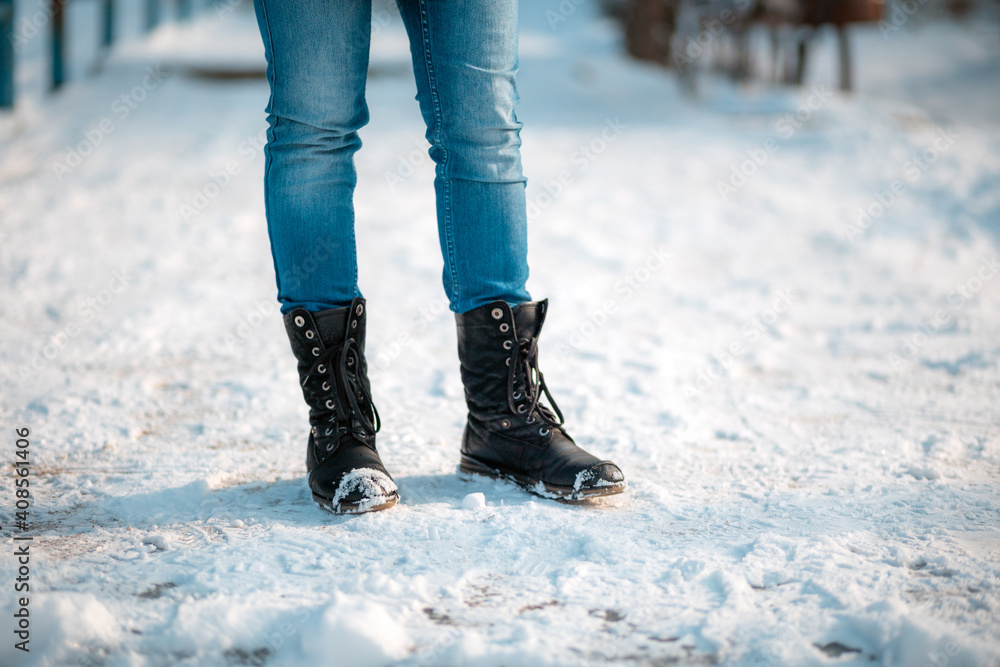 Female's feet in close-up, wearing boots with anti-slip protectors. Snow in the background. Copy space Female's feet in close-up, wearing boots with anti-slip protectors. Snow in the background. Copy space