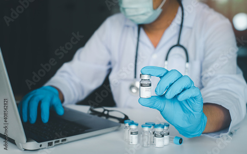 Doctor or scientist in laboratory or hospital holding a liquid vaccines and using laptop for research ,diseases,medical care,science. Fight against virus covid-19 corona virus concept.