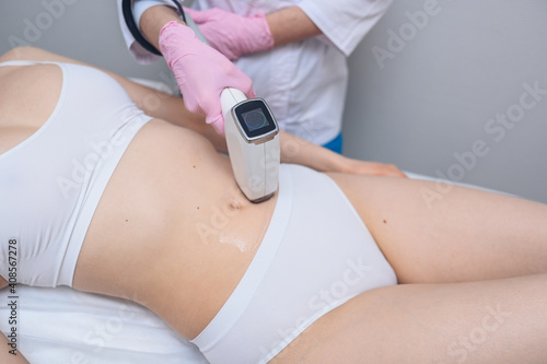 Laser epilation and cosmetology in beauty salon. Hair removal procedure. Laser epilation, cosmetology, spa, and hair removal concept. Beautiful blonde woman getting hair removing on abdomen.