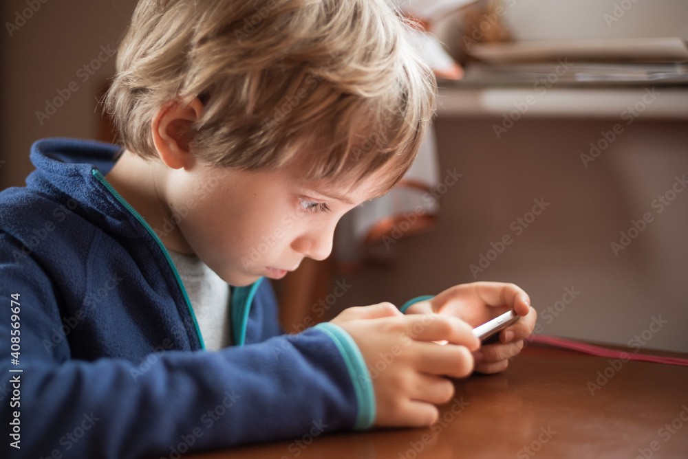 Young cute boy looking aat smartphone from short distance.
