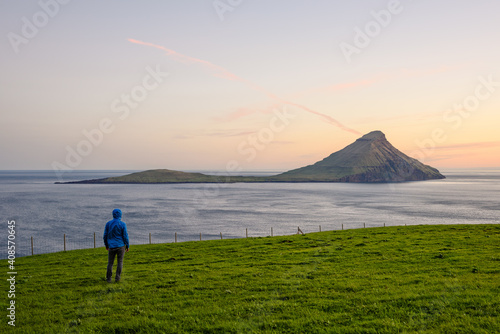 Tourist observing rocky island from grassy coast photo