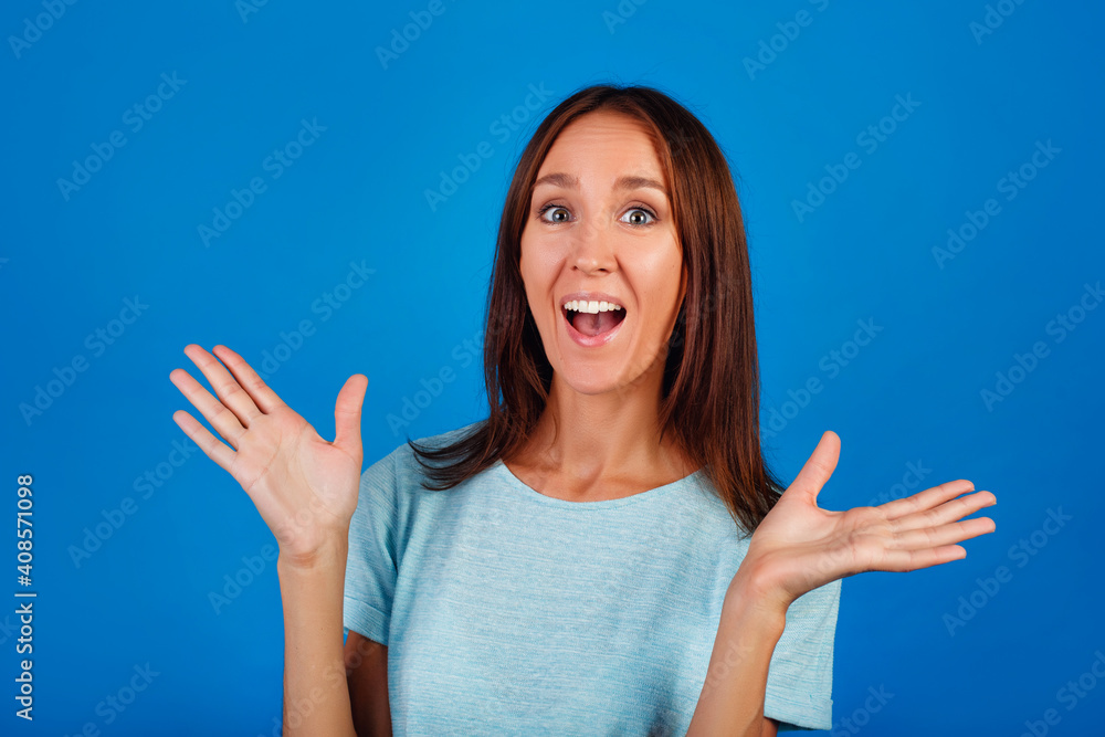Close-up photo of an impressed lady showing hand gestures, wearing a blue t-shirt isolated on a blue background Close-up photo of an impressed lady showing hand gestures, wearing a blue t-shirt isolated on a blue background