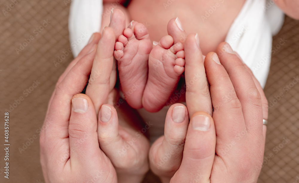 Bare feet of newborn surrounded by family members hands Bare feet of newborn surrounded by family members hands