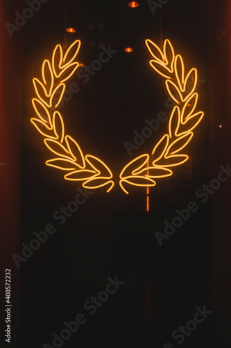 Laurel wreath designed with orange neon lights. Interior decoration concept.