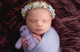 Newborn wearing diadem sleeping with toy