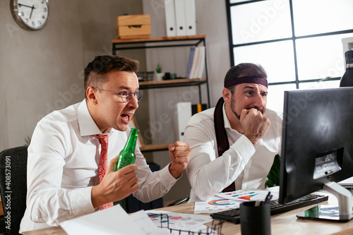 Two friends drinking beer in office. Colleagues are celebrating a big accomplishment at work..