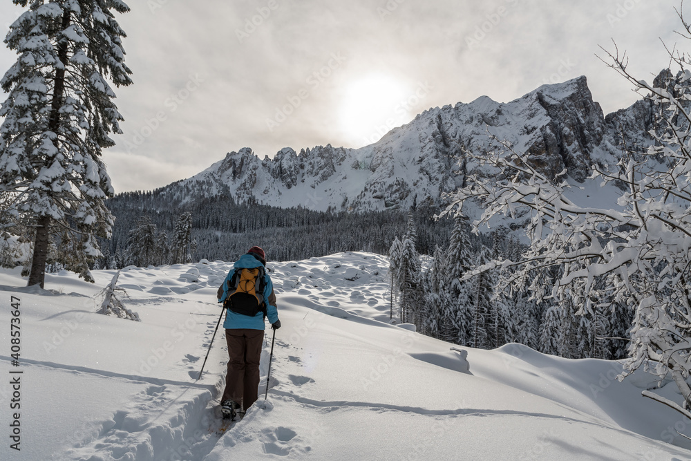 Girl hiking with snowshoes in the Rosengarten-Schlern group (Gruppo Catinaccio Sciliar) and the village of Karersee Carezza in the Dolomites in Italian Alps, Südtirol, Alto Adige in winter with snow