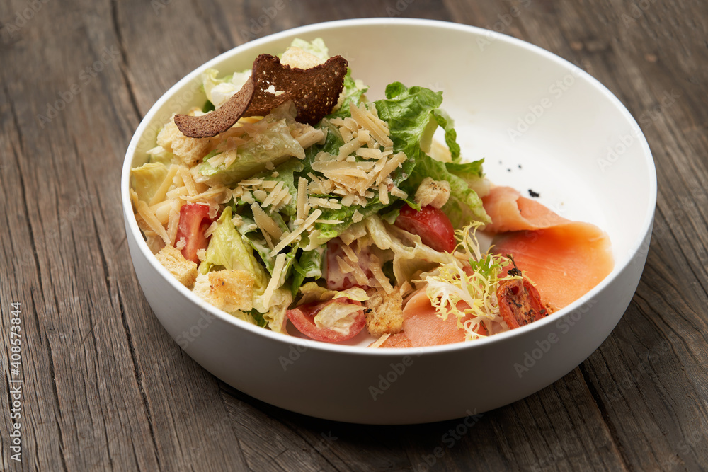 Caesar salad with salmon fish on white bowl Caesar salad with salmon fish on white bowl
